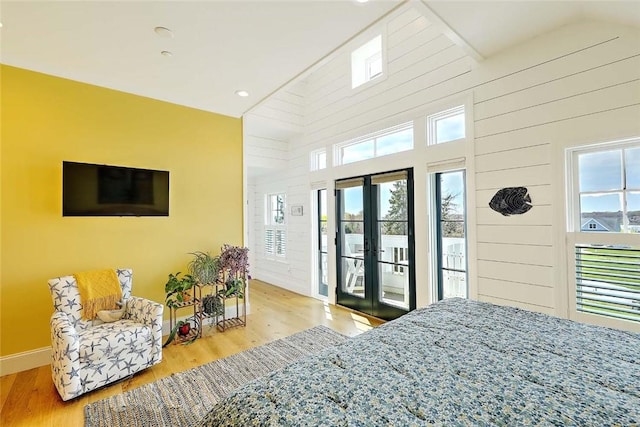 bedroom featuring wood finished floors, baseboards, a high ceiling, access to outside, and french doors