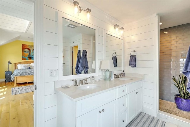 ensuite bathroom with connected bathroom, double vanity, a sink, and wood finished floors