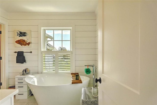 bathroom with a freestanding tub, tile patterned flooring, and wood walls