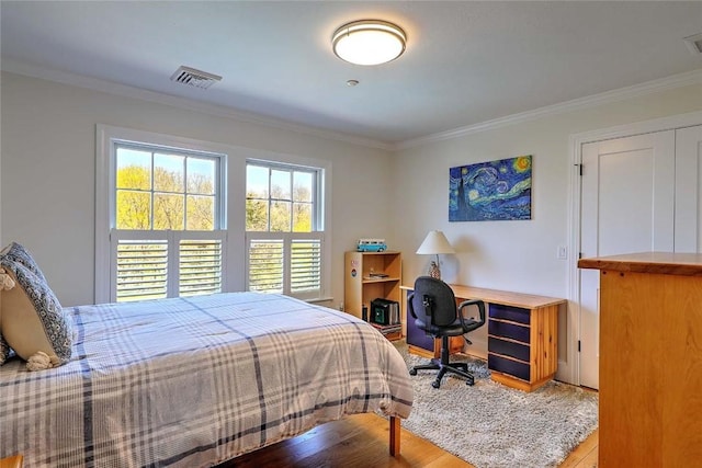 bedroom featuring crown molding, visible vents, and wood finished floors