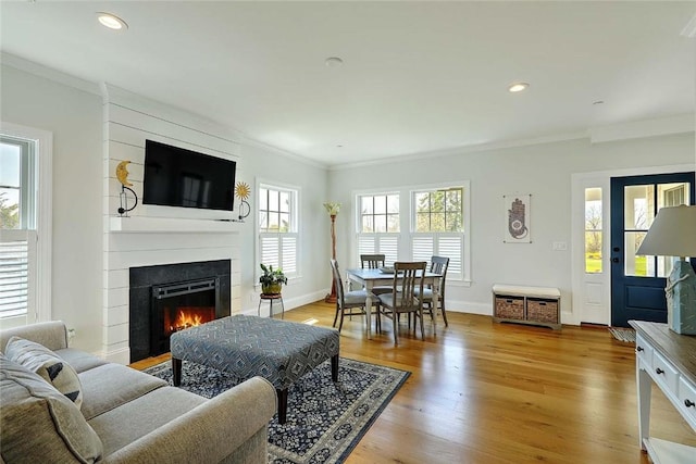 living area featuring crown molding, a fireplace, light wood-style flooring, recessed lighting, and baseboards