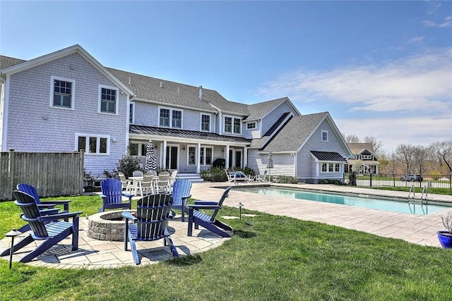 view of pool with fence, an outdoor fire pit, a fenced in pool, a patio area, and a lawn