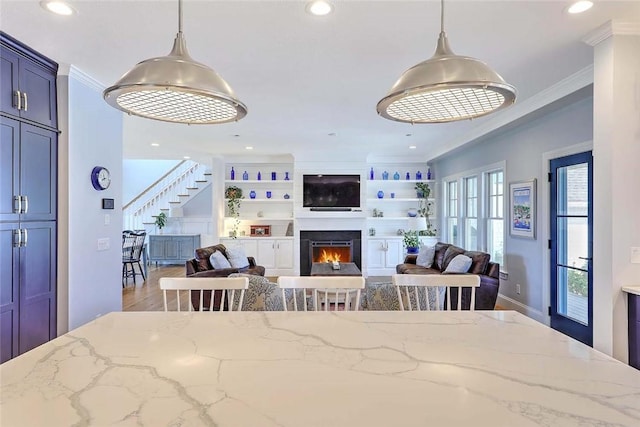 dining space with recessed lighting, ornamental molding, stairs, and a warm lit fireplace