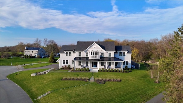 view of front facade with covered porch, a standing seam roof, metal roof, aphalt driveway, and a front lawn