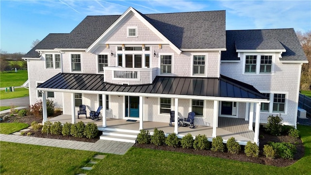rear view of house featuring a standing seam roof, a porch, and roof with shingles