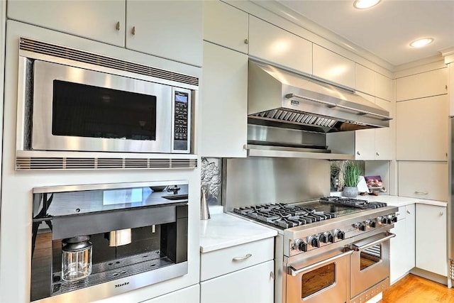 750 Elmgrove Ave, Providence, RI 02906 - kitchen with exhaust hood, backsplash, appliances with stainless steel finishes, light countertops, and light wood finished floors