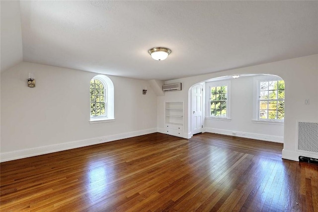 750 Elmgrove Ave, Providence, RI 02906 - spare room featuring arched walkways, plenty of natural light, an AC wall unit, and hardwood / wood-style flooring