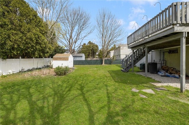 view of yard featuring a wooden deck, an outbuilding, a fenced backyard, a shed, and stairs