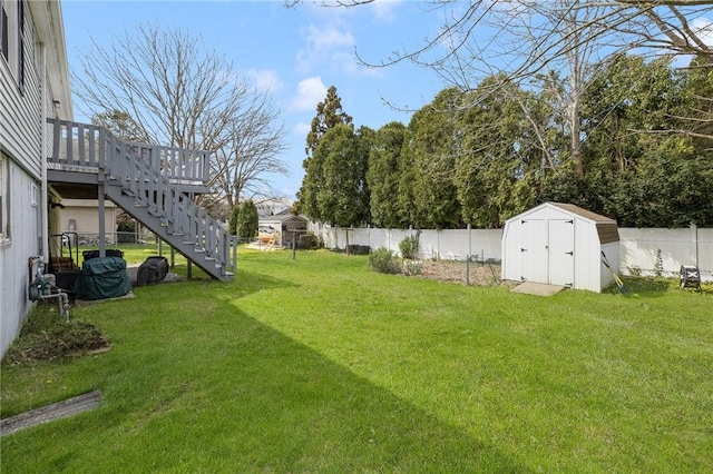 view of yard with a fenced backyard, an outbuilding, a storage shed, a wooden deck, and stairs