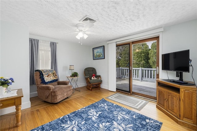 sitting room featuring visible vents, a textured ceiling, and light wood-style flooring