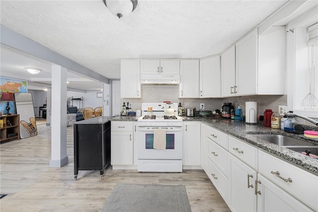 kitchen featuring white gas range, white cabinetry, under cabinet range hood, and light wood-style floors