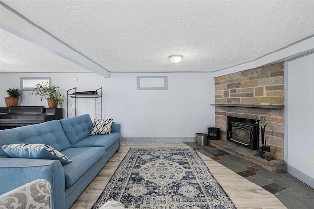 living area with a textured ceiling, wood finished floors, a wood stove, and baseboards