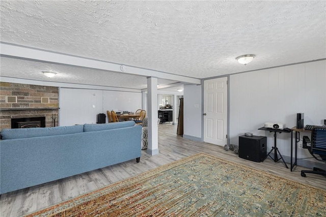 living room featuring wood finished floors, a textured ceiling, and a brick fireplace