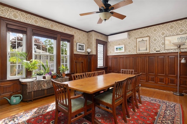 dining area with an AC wall unit, crown molding, wood finished floors, wainscoting, and ceiling fan