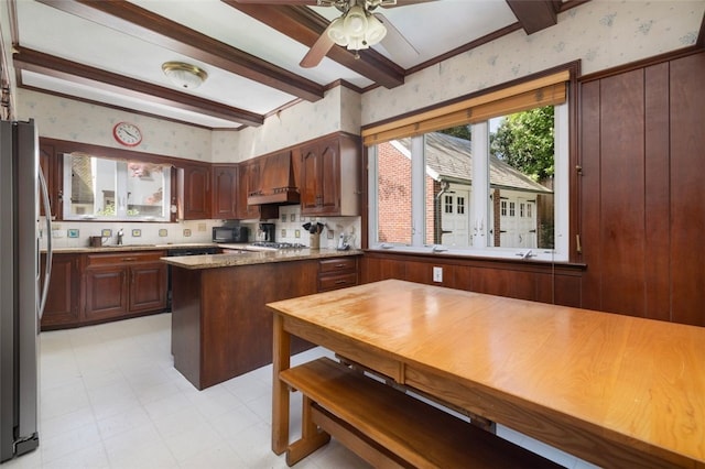 kitchen with wallpapered walls, appliances with stainless steel finishes, custom range hood, beamed ceiling, and light flooring