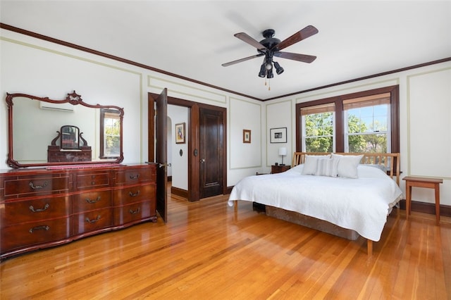 bedroom featuring crown molding, light wood-style floors, a decorative wall, baseboards, and a ceiling fan