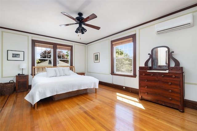 bedroom with a wall unit AC, multiple windows, light wood-style flooring, ornamental molding, and ceiling fan