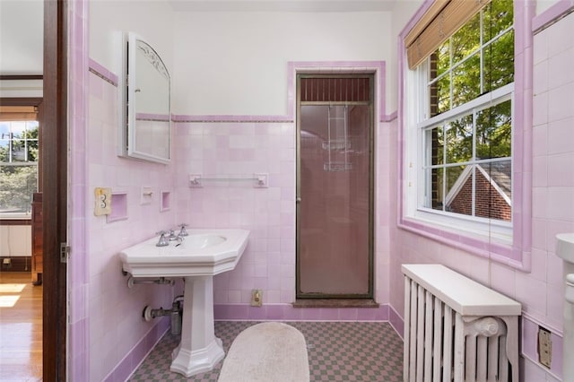 full bath featuring radiator, tile walls, a stall shower, plenty of natural light, and tile patterned floors