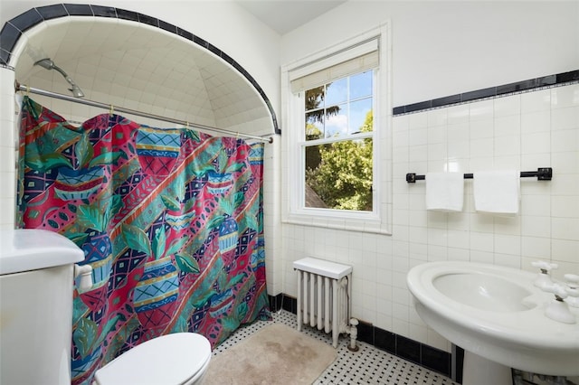 full bathroom with radiator, tile walls, toilet, a shower with curtain, and a sink