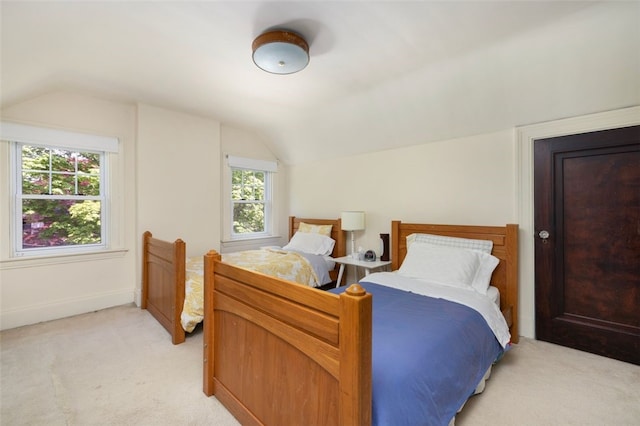 bedroom with vaulted ceiling, light carpet, and baseboards