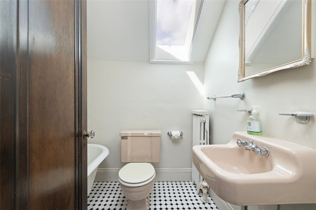 bathroom with toilet, baseboards, and a bath