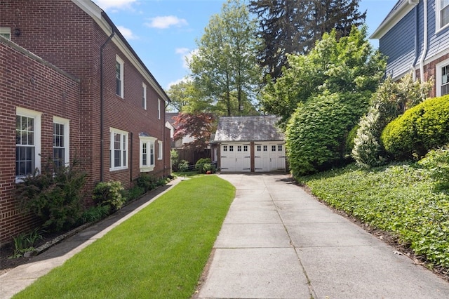 view of side of property with an outbuilding, a garage, brick siding, and a yard