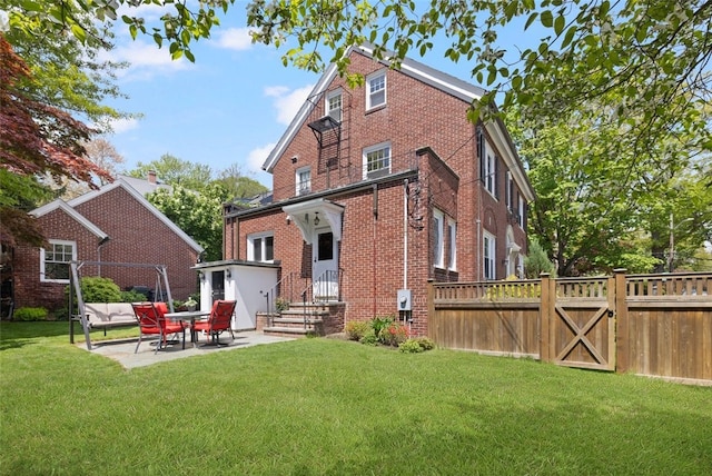 back of house with brick siding, a patio area, and a gate