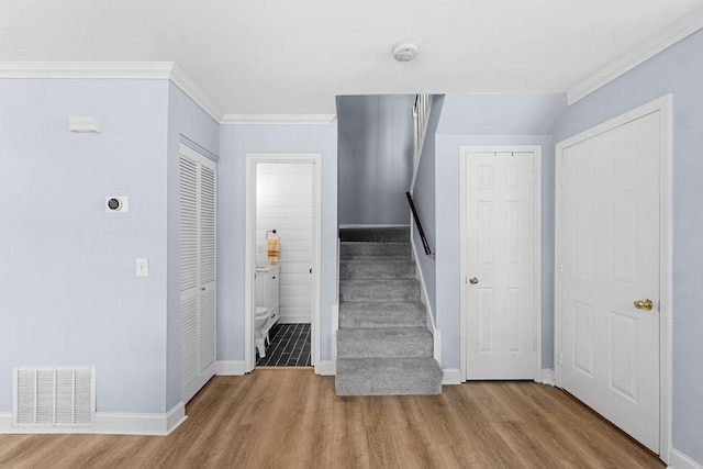 stairway featuring ornamental molding, visible vents, wood finished floors, and baseboards