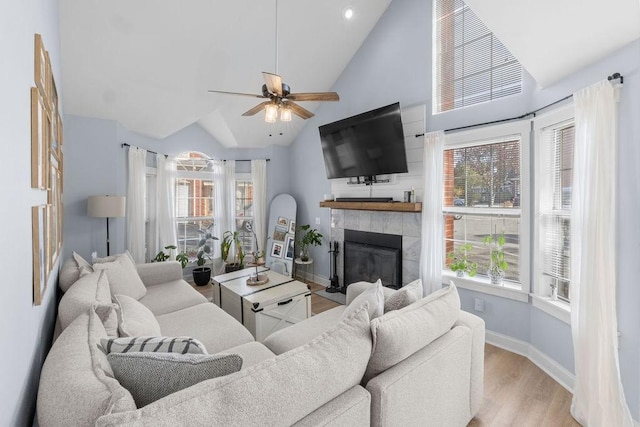 living area featuring baseboards, a wealth of natural light, ceiling fan, and a fireplace