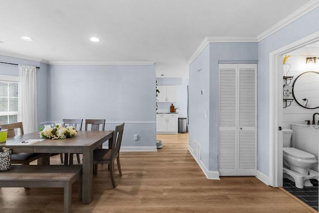 dining space with light wood-style floors, crown molding, recessed lighting, and baseboards