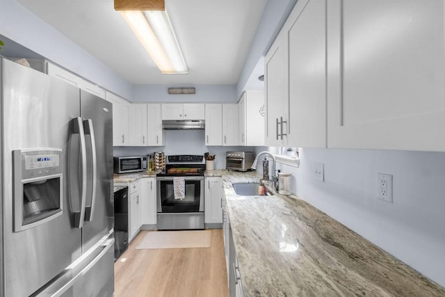 kitchen with light stone countertops, a sink, stainless steel appliances, under cabinet range hood, and white cabinetry