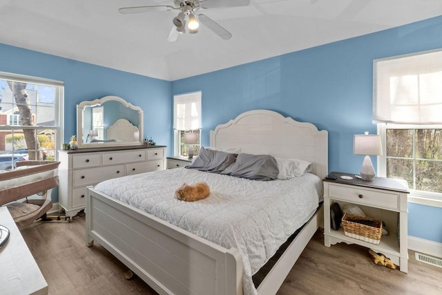 bedroom featuring wood finished floors, visible vents, ceiling fan, and multiple windows