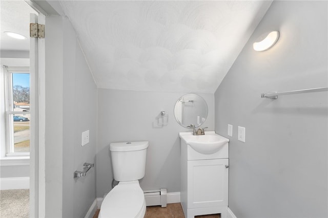 half bath with a baseboard heating unit, toilet, and baseboards
