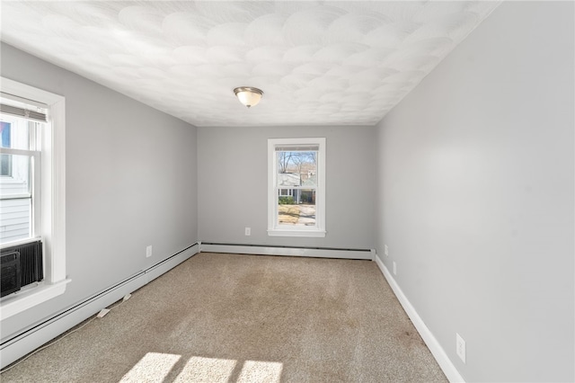 empty room with a baseboard heating unit, carpet flooring, and baseboards