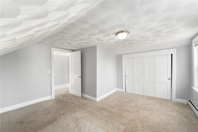 unfurnished bedroom featuring a textured ceiling, a baseboard radiator, a closet, baseboards, and carpet