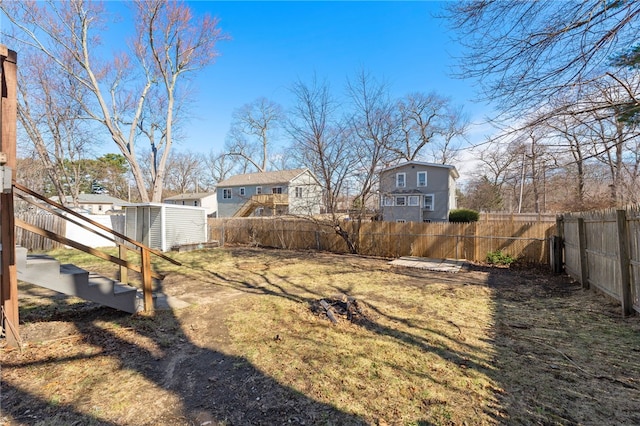 view of yard featuring an outdoor structure, a shed, a residential view, and a fenced backyard