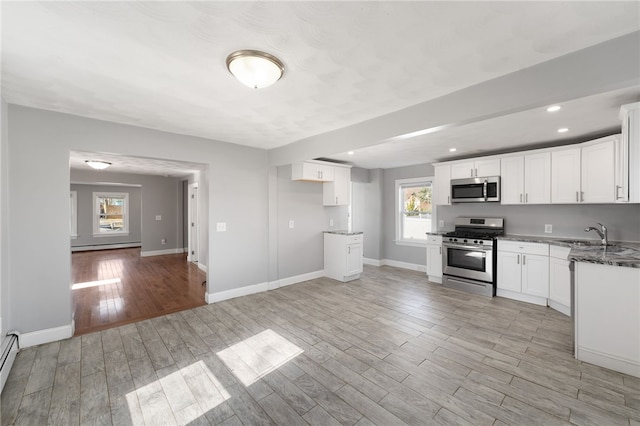 kitchen featuring light wood-style floors, stainless steel appliances, white cabinetry, and baseboards