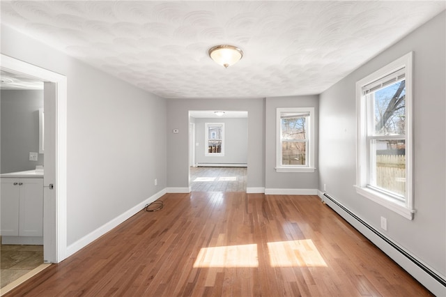 unfurnished dining area with baseboards, light wood-style floors, and a baseboard radiator
