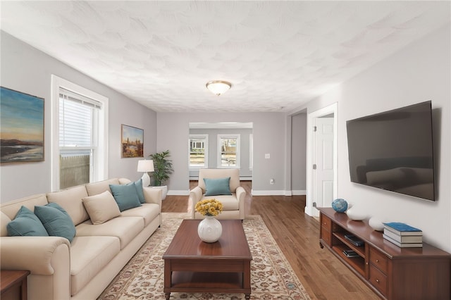 living room with a baseboard heating unit, a textured ceiling, baseboards, and dark wood-type flooring
