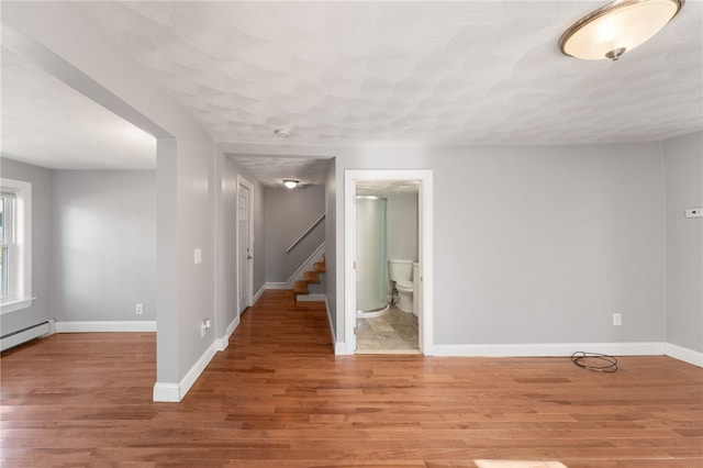 empty room with light wood-style flooring, stairs, and baseboards