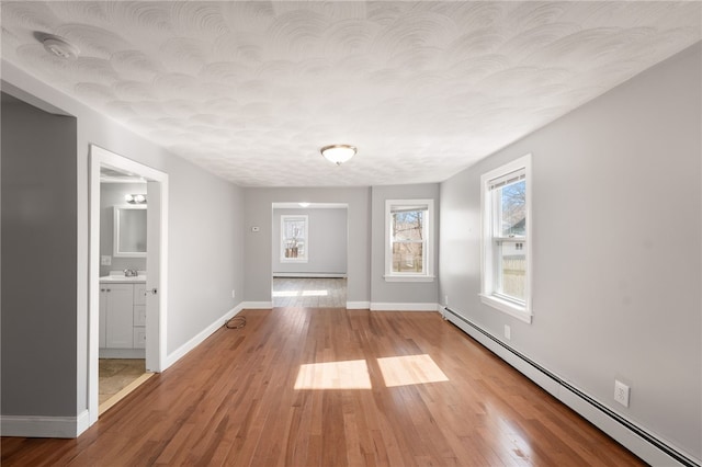 unfurnished dining area with baseboards, wood finished floors, and a baseboard radiator