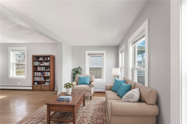 living room with baseboard heating, wood finished floors, and baseboards
