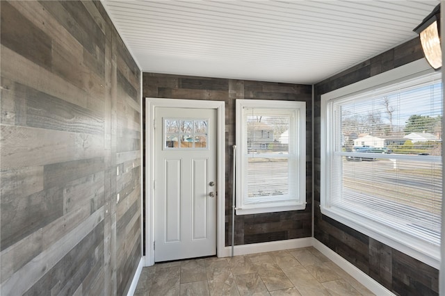 entrance foyer with wooden walls, plenty of natural light, and baseboards