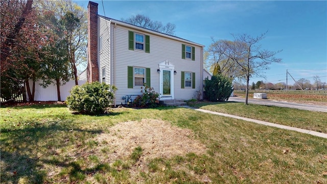 colonial home with a chimney and a front lawn
