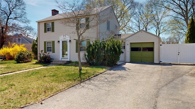 colonial inspired home featuring an attached garage, a front lawn, aphalt driveway, entry steps, and a chimney
