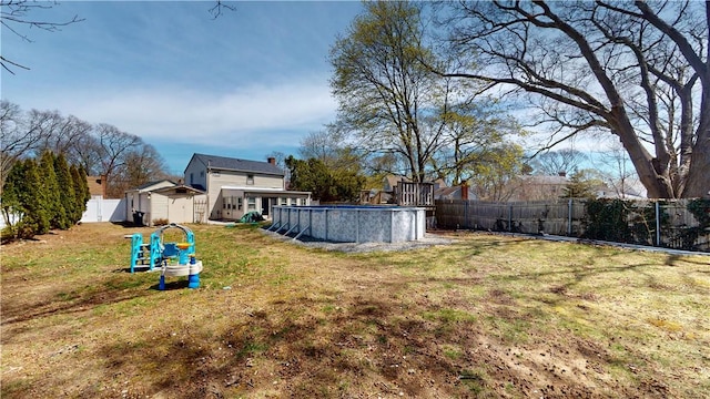 view of yard featuring a fenced backyard, a fenced in pool, an outdoor structure, and a shed