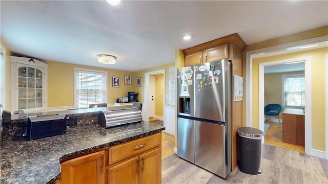 kitchen with stainless steel refrigerator with ice dispenser, a healthy amount of sunlight, and light wood-type flooring