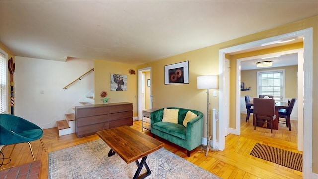 living area with baseboards, stairs, and hardwood / wood-style floors