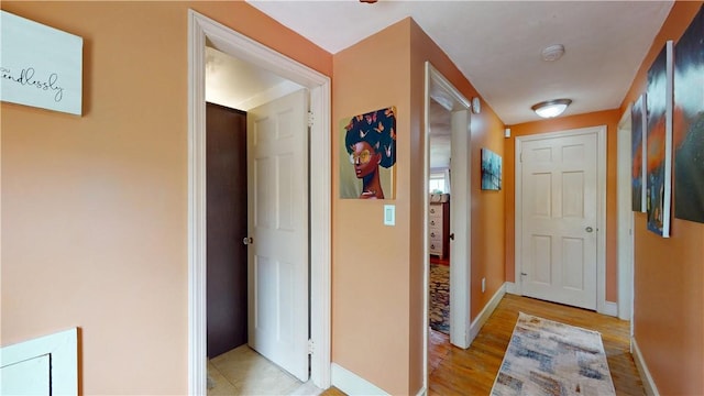 corridor featuring light wood-style floors and baseboards