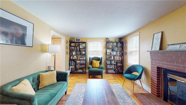 living area with a brick fireplace and wood finished floors